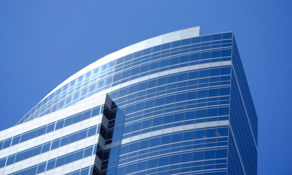 A vertical low angle shot of a modern business building touching the clear sky